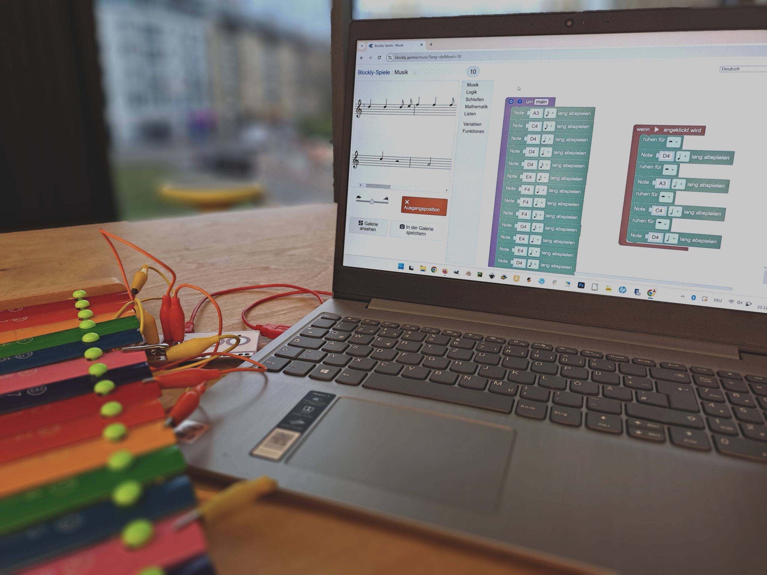 Ein Laptop mit dem geöffneten Programm "Block Music", der über ein Makey Makey mit einem Metallophon verbunden ist.