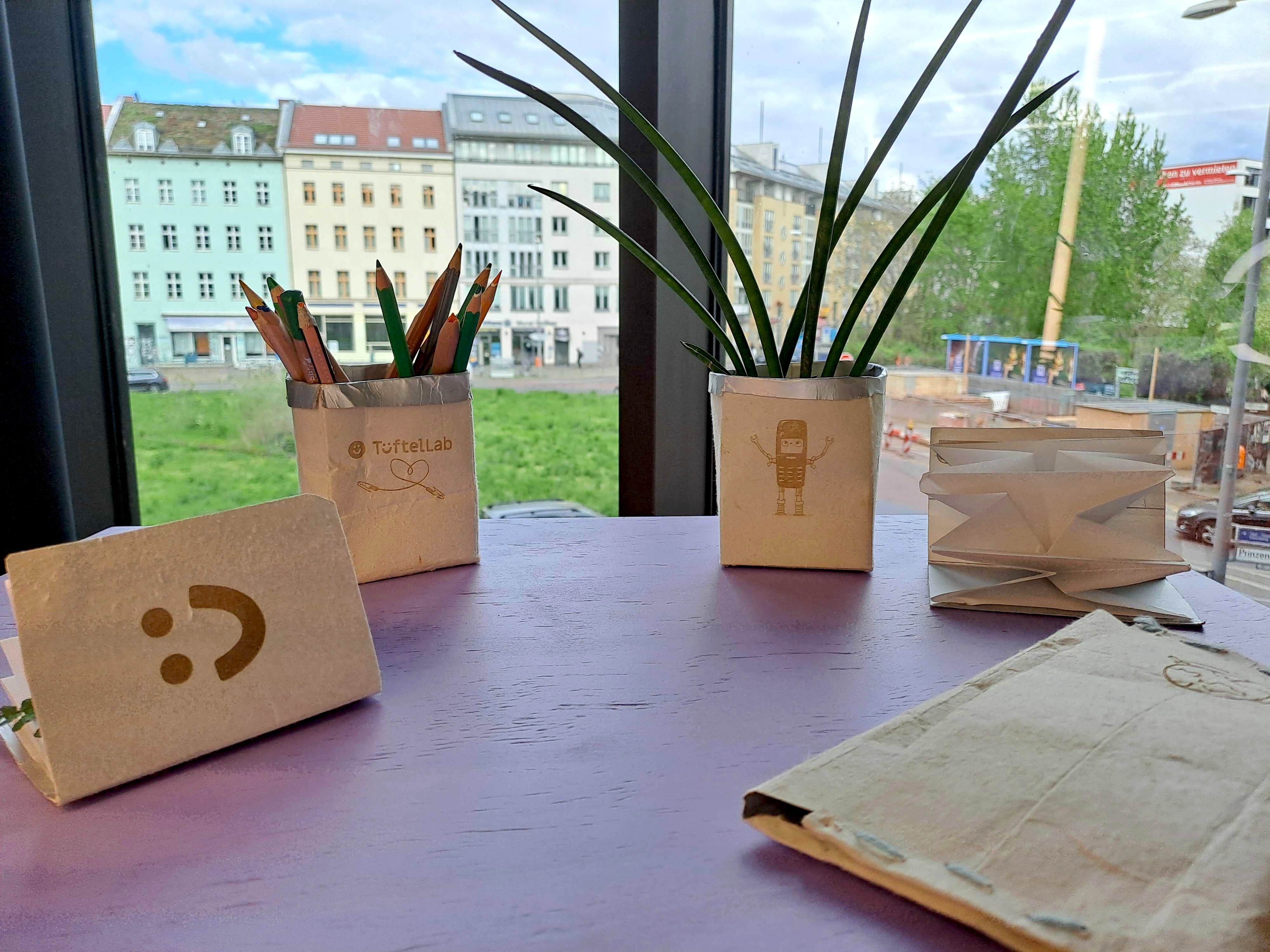 Verschiedene Kreationen mit Tetrapaks: ein Blumentopf, ein Federmäppchen und Pflanzendrucke.